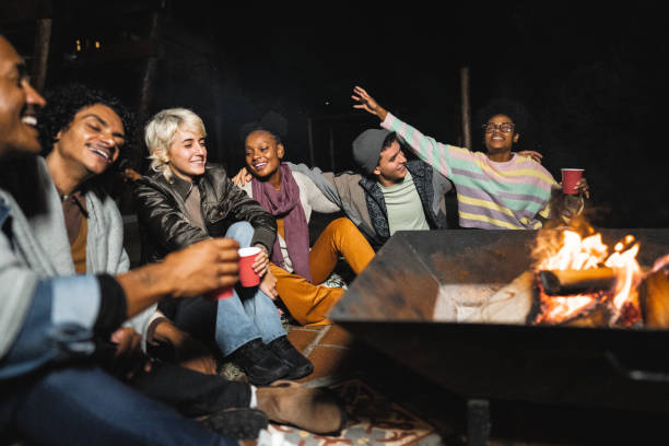 istock Friends a having fun sitting around of a fire pit on yard at night 2099857342