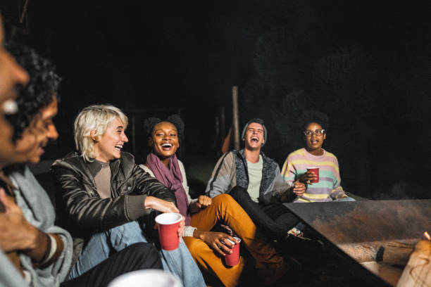 istock Friends a having fun sitting around of a fire pit on yard at night 2099857865