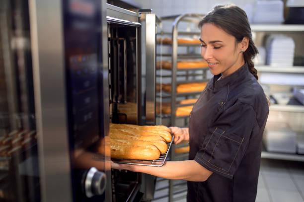istock Woman baker using electrical oven for baking French baguettes 2099860616