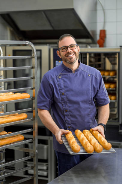 istock Man baker baking and selling tasty breads 2099860650