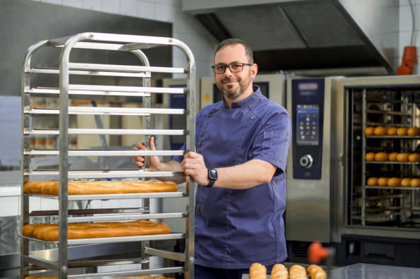 istock Man baker baking and selling tasty breads 2099860655