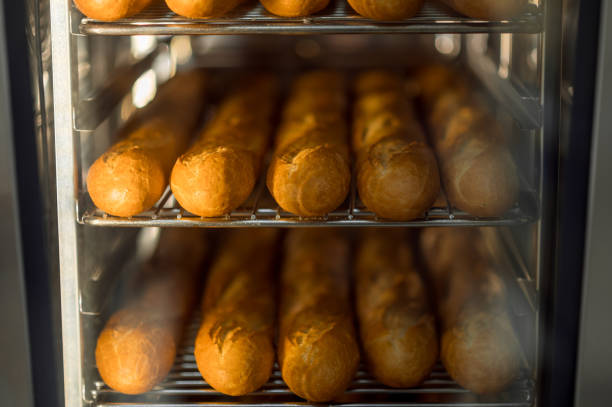 Cooking fresh crispy baguettes in oven at commercial bakery