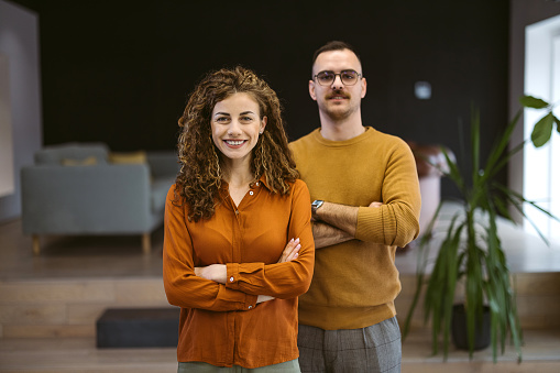 Portrait of two business people standing in an office and looking at the camera