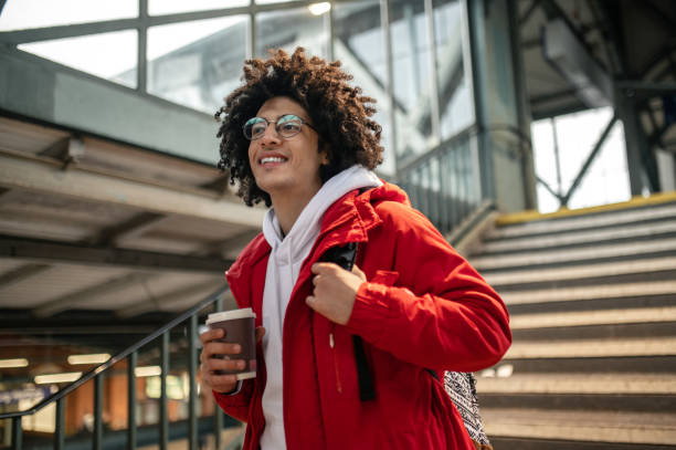 istock Curly-haired young guy holding a coffee cup and looking excited 2099886238
