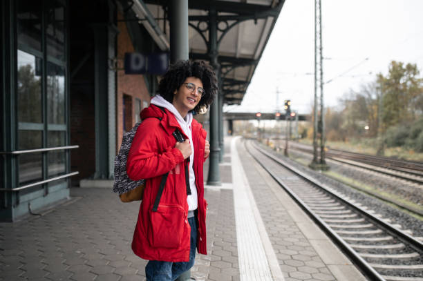 istock Guy in red jacket and with backpack waiting for the train at the platform 2099886261