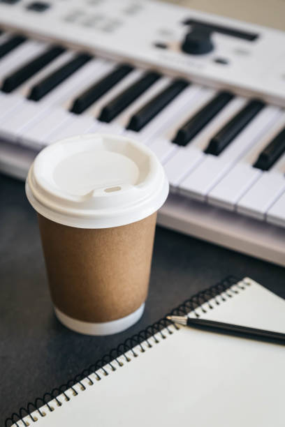 istock Musician workplace table with paper cup and white piano keyboard. 2099890056