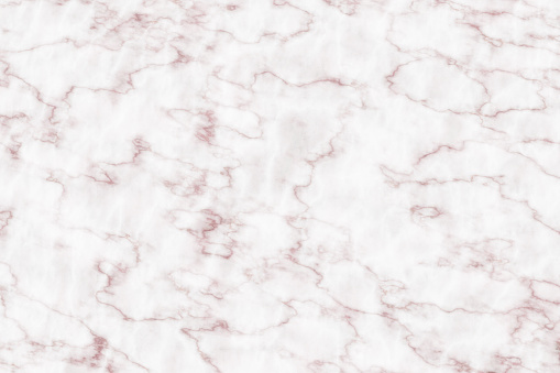 A close-up view of white marble with a gentle pattern of pink and gray veins creating a luxurious and refined natural background texture. The surface depicts the intricacies and beauty found in natural stone materials, commonly used in design and architecture.