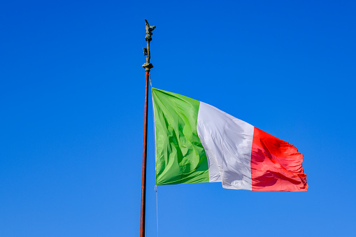 Itallian flag over blue sky in Rome