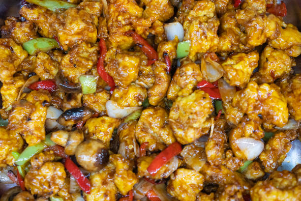 Stir Fried Chicken with Cashew Nuts, Close-up of cashew chicken stir-fry with bell peppers, dry chili, onions, and crispy chicken pieces on white background, Thai food