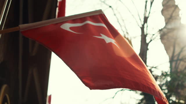 Turkish flag waving under the summer breeze with visible minaret and mosque at the background