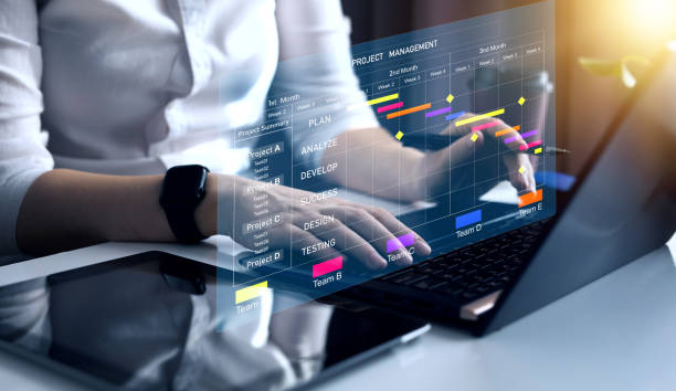istock Project manager working on laptop and updating tasks and milestones progress planning with Gantt chart scheduling interface for company on virtual screen. Business Project Management System. 2099989415