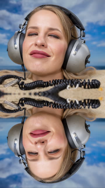 Woman buried in sand on beach with headphones vertical