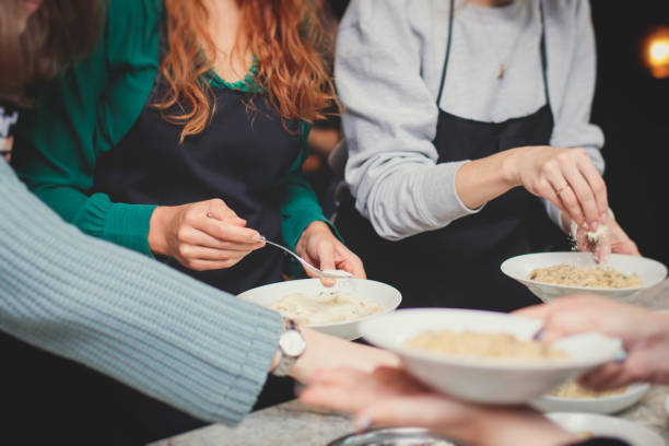 istock Group of people in a cooking class studio, adults preparing different dishes in the kitchen together, people in aprons learn on culinary master class, chef uniform, hands in gloves, italian cuisine 2100009840