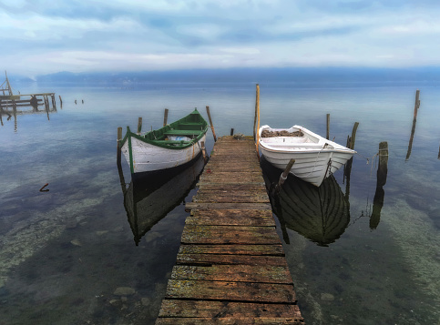 Morning fog on a lake with a wooden pier and moored boats