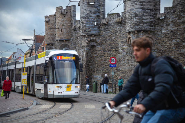 Ghent, Belgium—Nov 22 2023: a tram driving through Gravensteen and a man cycling by in winter