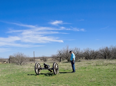 Senior Man looking at old Cannon is one of the  last  of the remains at Ft. Phantom  in Jones County TX not far from Abilfene, TX