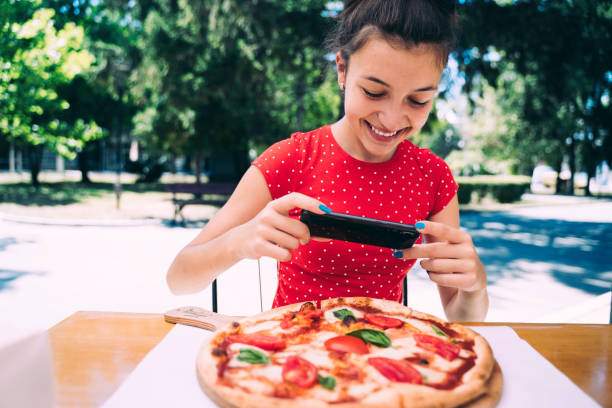 istock Teenager eating pizza looking in phone. Using phone. 2100152975