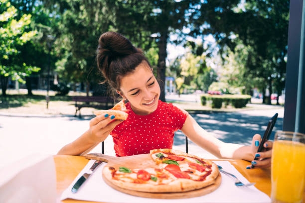 istock Teenager eating pizza looking in phone. Using phone. 2100152979