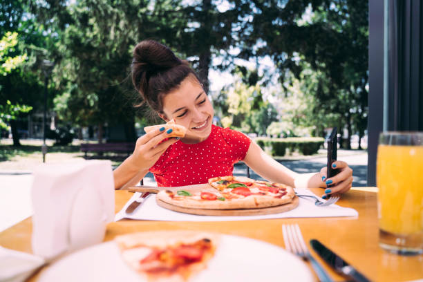 istock Teenager eating pizza looking in phone. Using phone. 2100152980