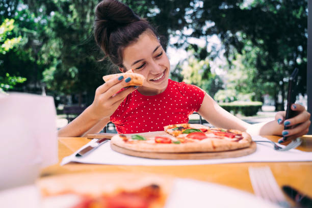 istock Teenager eating pizza looking in phone. Using phone. 2100152983