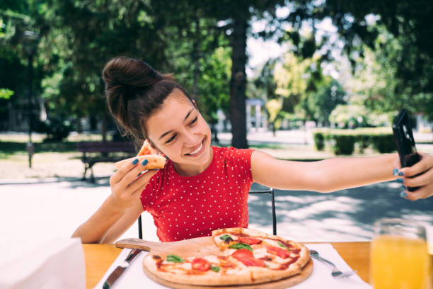 istock Teenager eating pizza looking in phone. Using phone. 2100152986