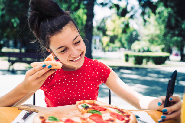 istock Teenager eating pizza looking in phone. Using phone. 2100152991