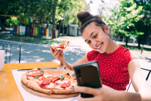 istock Teenager eating pizza looking in phone. Using phone. 2100152995