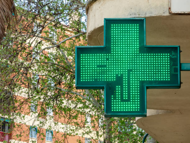 istock Health Signal: Pharmacy's Green Cross on Cityscape. 2100186916