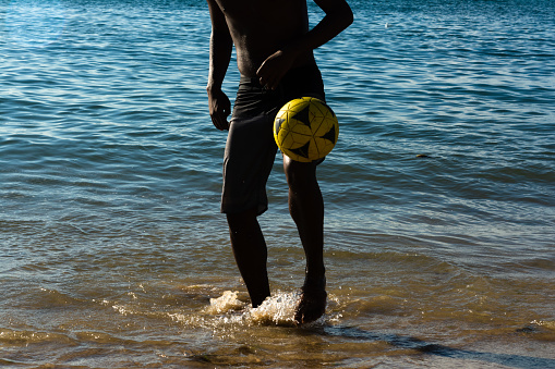 Salvador, Bahia, Brazil - March 09, 2019: A young man is seen playing beach soccer on Riberia beach in the city of Salvador, Bahia.