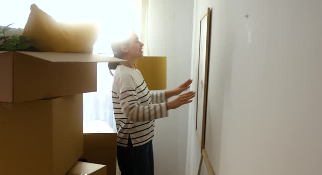 Woman hanging the picture on the wall in new apartment