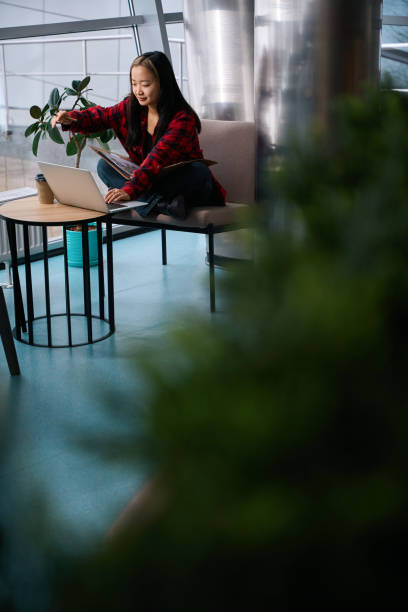 istock Asian female IT employee taking coffee while working with notebook and laptop 2100216844