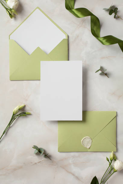 Wedding stationery set. Flat lay olive envelopes, blank wedding invitation card, flowers on marble background.