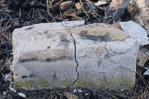 one white large old brick with a crack stands on the ground