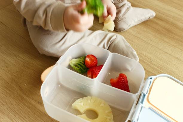 istock A baby boy sits on the floor and eats food from a plastic tray 2100253667