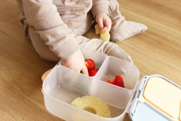 istock A baby boy sits on the floor and eats food from a plastic tray 2100257382