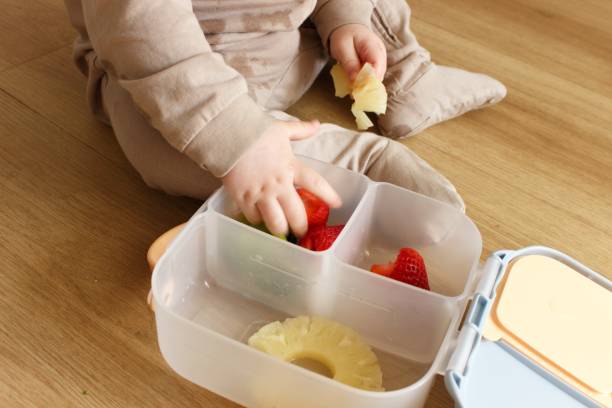 istock A baby boy sits on the floor and eats food from a plastic tray 2100258420