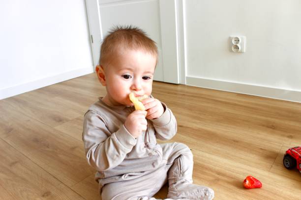 istock A baby boy sits on the floor and eats food from a plastic tray 2100261492