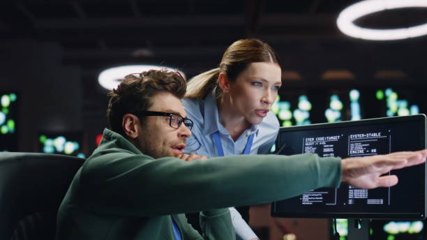 istock Programmers couple working together in dark room closeup. Analysts discussing 2100278581