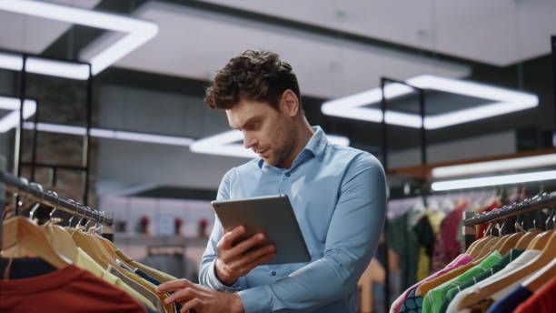 istock Shop worker checking tablet doing inventory mall closeup. Man working boutique 2100325560