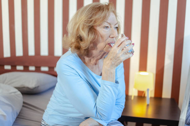 istock Senior woman drinking water in bedroom 2100358551