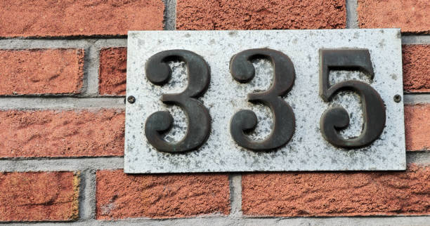 istock Number plate. Number 335 against a red brick wall background. 2100390385