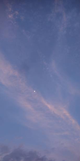 istock The moon is covered by thin clouds against a blue sky background 2100412429