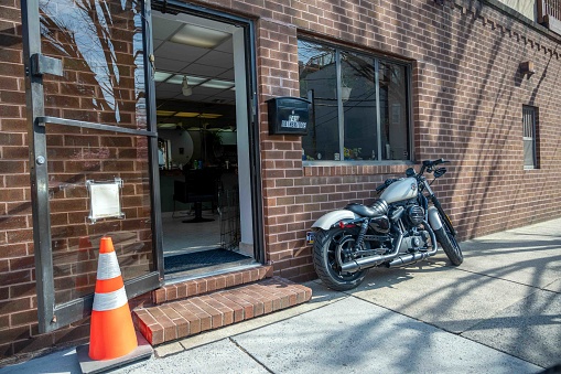 Philadelphia, Pennsylvania, USA 03-14-2024 Bainbridge Street. A white Harley Davidson motorcycle parked against a brick exterior of a salon. Door is propped open with a traffic cone. Editorial use only