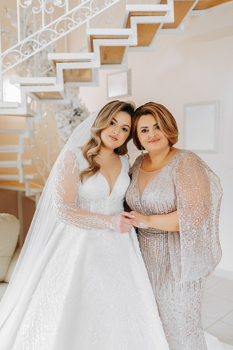 A beautiful and happy mother and her daughter, the bride, are standing next to each other. The best day for parents. Tender moments at the wedding.