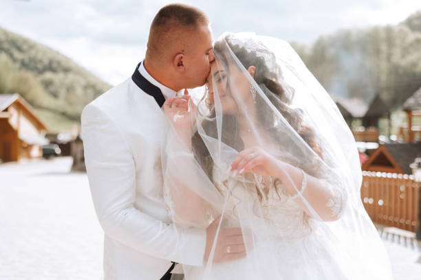 istock Wedding. Love and couple in garden for wedding. Celebration of ceremony and commitment. Save the date. Trust. The bride and groom embrace. The groom embraces the bride under the veil. 2100514792