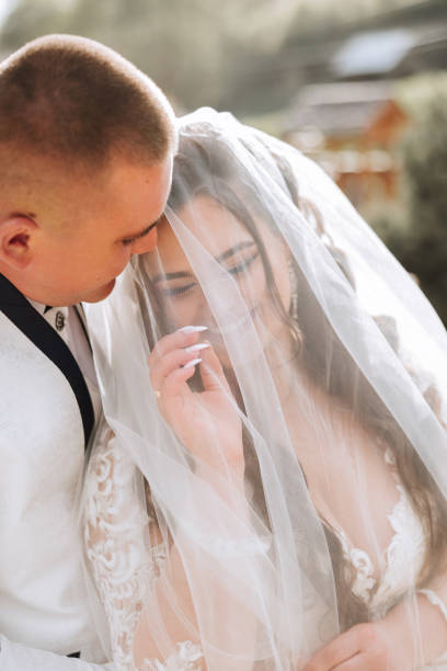 istock Wedding. Love and couple in garden for wedding. Celebration of ceremony and commitment. Save the date. Trust. The bride and groom embrace. The groom embraces the bride under the veil. 2100514838