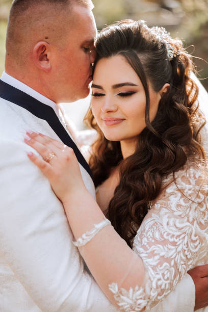 istock Wedding. Love and couple in garden for wedding. Celebration of ceremony and commitment. Save the date. Trust. The bride and groom embrace. Smile and love in the park. The groom embraces the bride. 2100515292