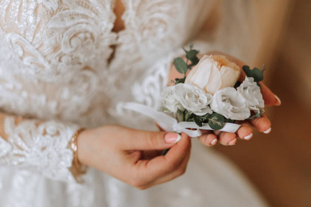 wedding boutonniere in the hands of the bride. the first meeting of the bride and groom. the bride puts on a bootie over the groom's jacket - glove formal glove white wedding - fotografias e filmes do acervo