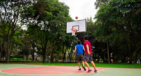 Friends playing basketball in court in sunny day at summer