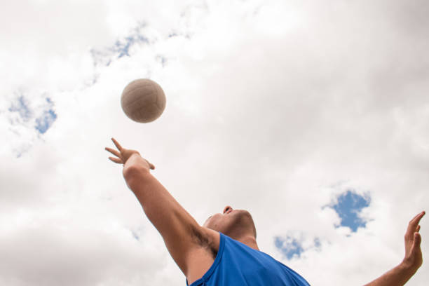Low angle view of man playing with volleyball ball in sunny day